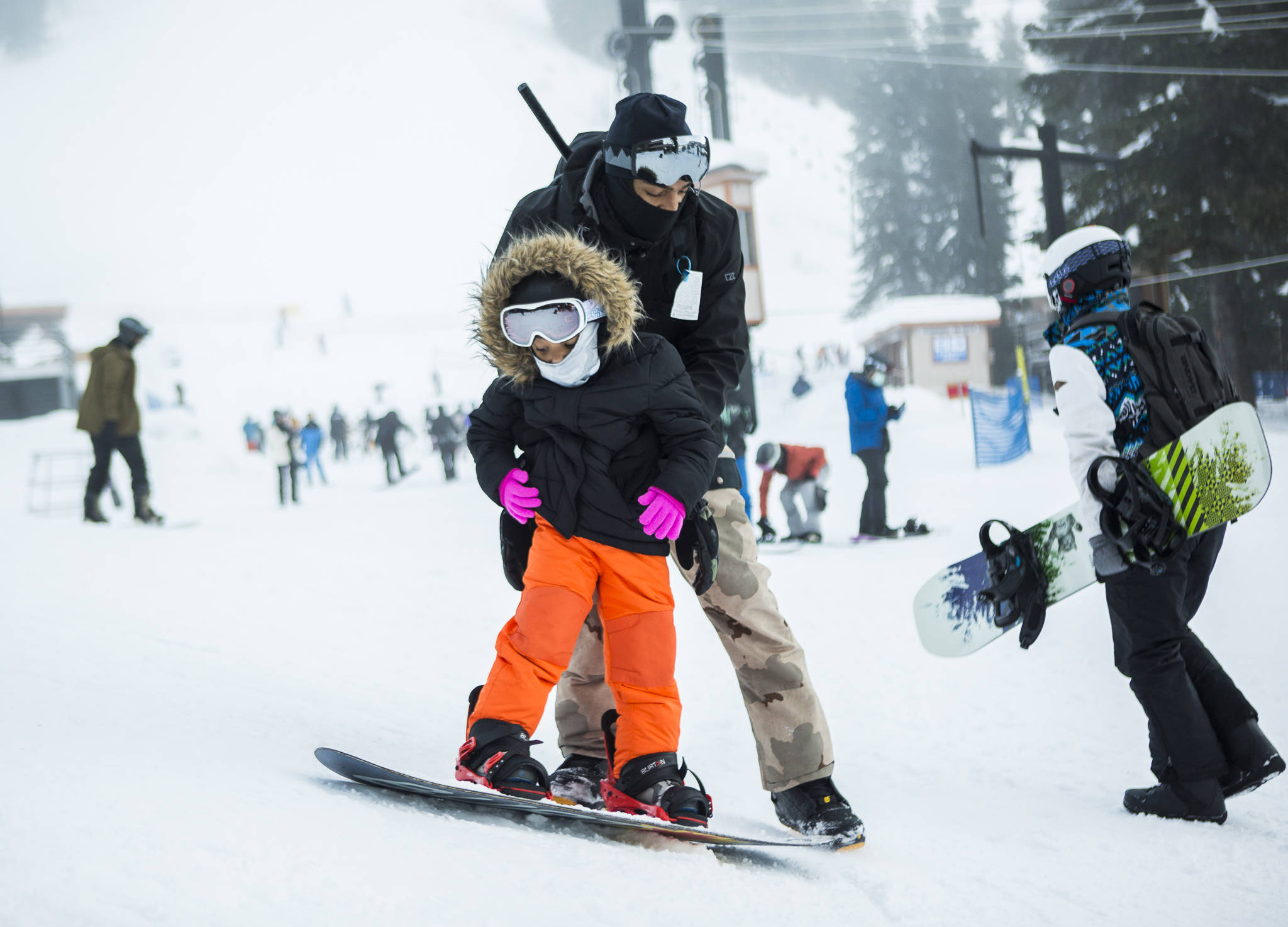 On opening day at Steven’s Pass on Friday, Jarrell Banks helps his daughter, Londyn, 4, learn how to stop during her first time snowboarding. (Olivia Vanni / The Herald)