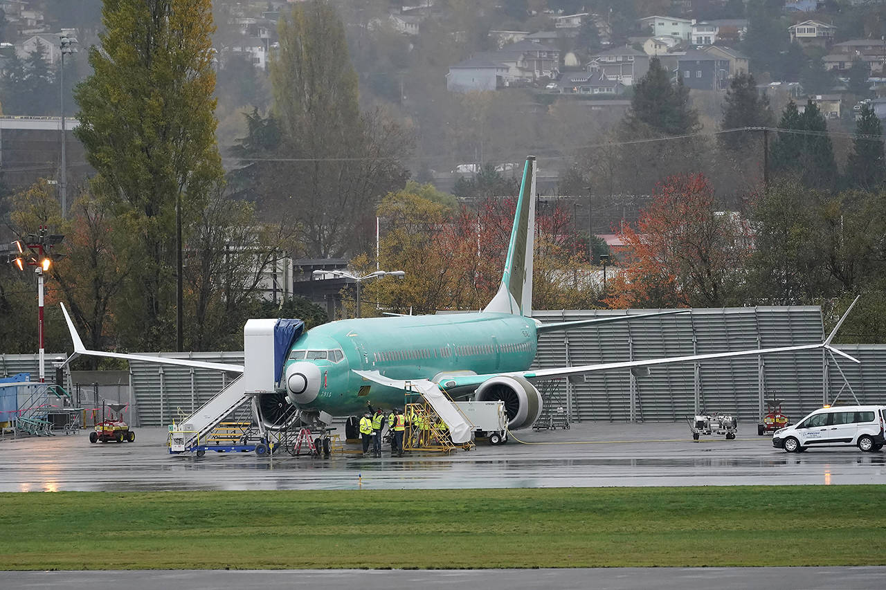 Workers stand near a Boeing 737 Max airplane parked at Renton Municipal Airport on Nov. 18, next to the Boeing assembly facility in Renton. (AP Photo/Ted S. Warren, file)