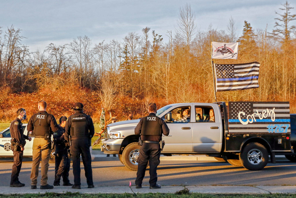 Law enforcement officers watch the procession of a memorial parade for missing Tulalip officer Charlie Cortez Saturday afternoon on the Tulalip Reservation. (Kevin Clark / The Herald)
