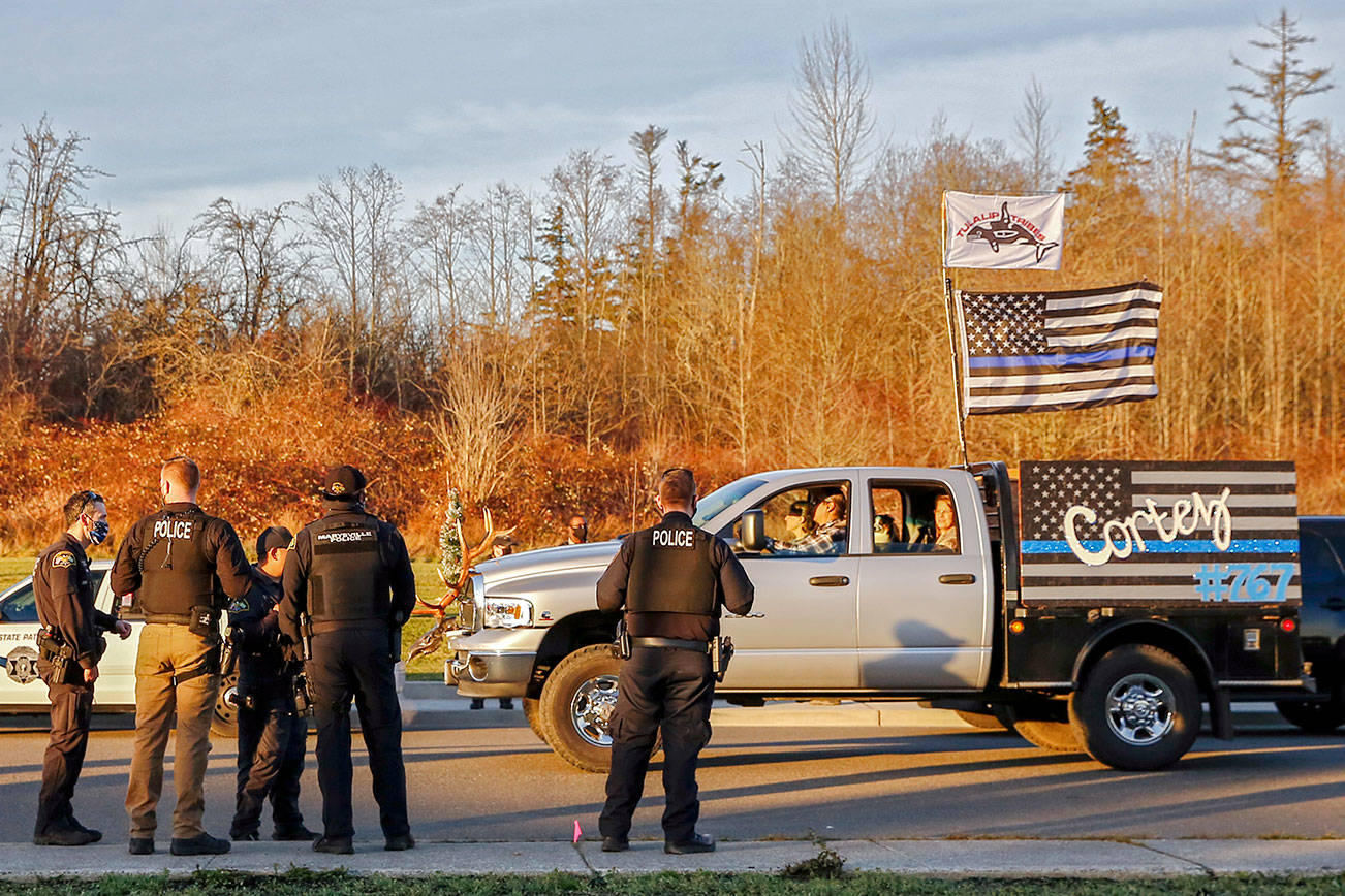 Law enforcement officers watch the procession of the memorial parade for fallen and missing Tulalip officer Charlie Cortez Saturday afternoon on the Tulalip Reservation on December 12, 2020.  (Kevin Clark / The Herald)