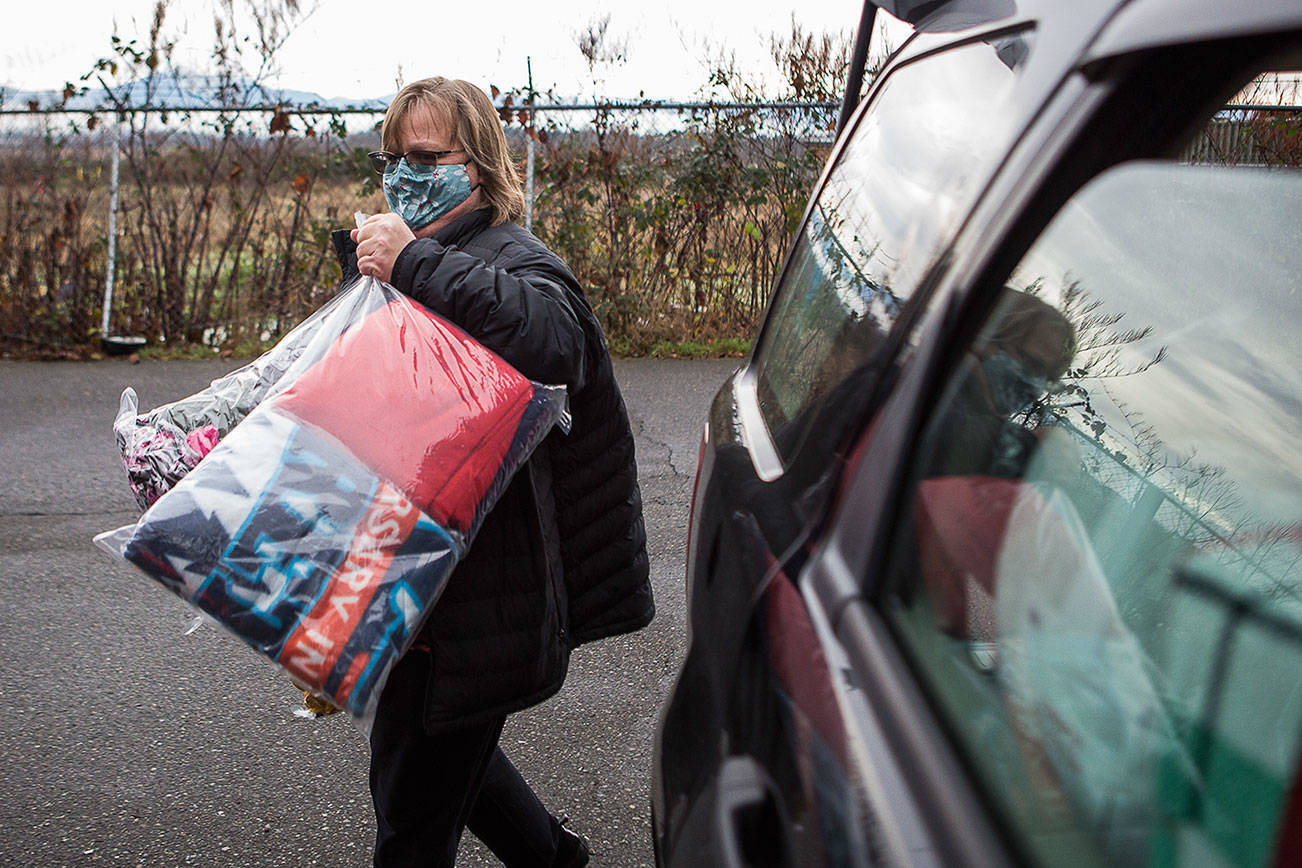 Tonja Jones unloads bags of coat donations outside of the Everett Gospel Mission on Thursday, Dec. 10, 2020 in Everett, Wa. (Olivia Vanni / The Herald)