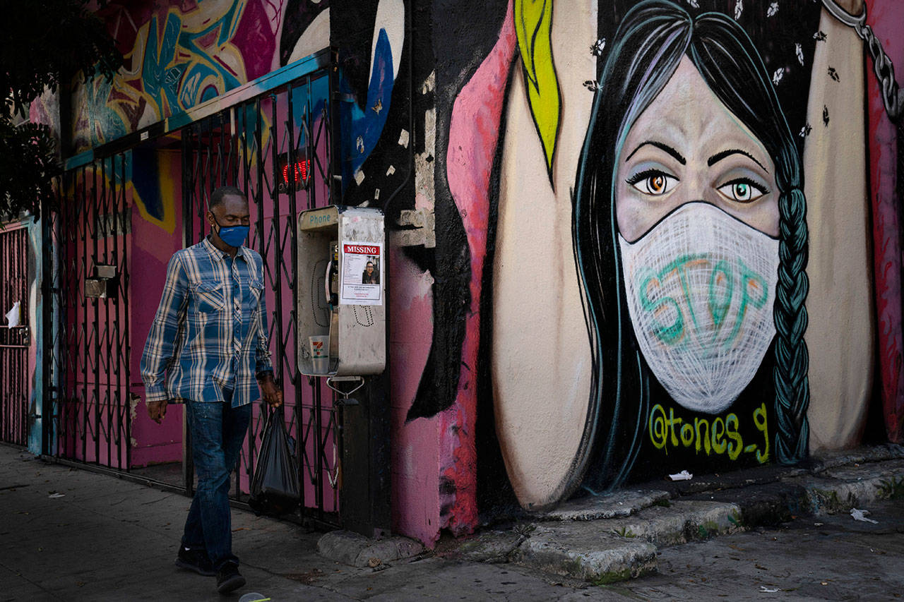 A man wearing a face mask walks past a mural Oct. 1, in South Central Los Angeles. (Jae C. Hong / Associated Press)