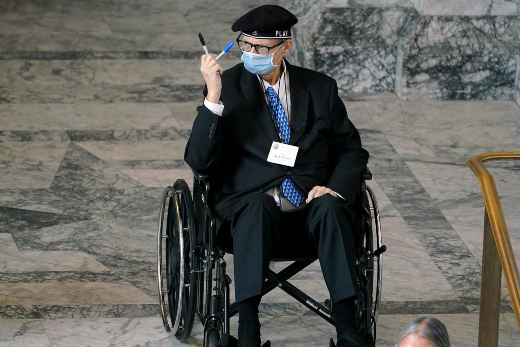 Jack Arends, a member of Washington’s Electoral College from Everett, holds up the markers he used to cast his votes for the president and vice president of the United States at the state Capitol in Olympia on Monday as he waits to take part in a group photo. (AP Photo/Ted S. Warren)

