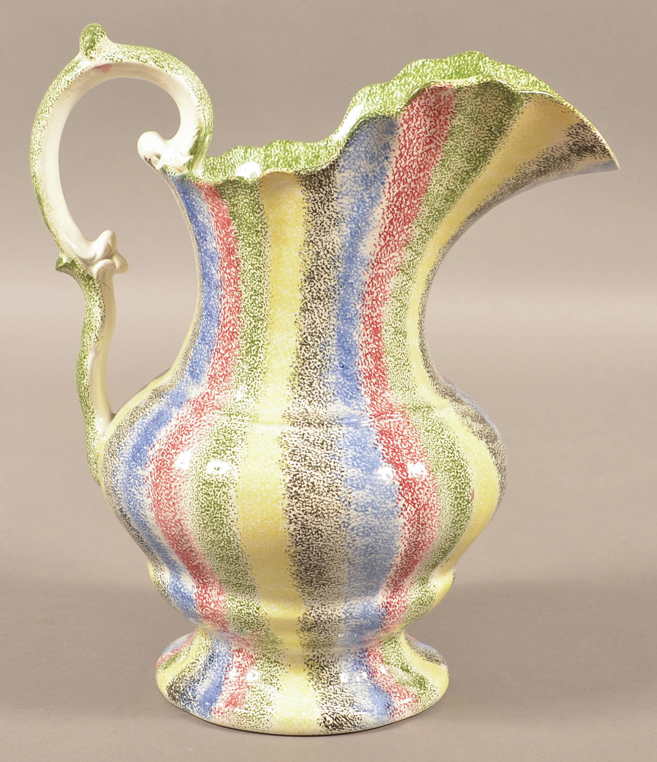 This 11-inch-high antique rainbow spatterware water picture with bands in five different colors sold for more than $5,000 at a Conestoga auction this year. Notice the double G-scroll handle, an added value feature. (Cowles Syndicate Inc.)