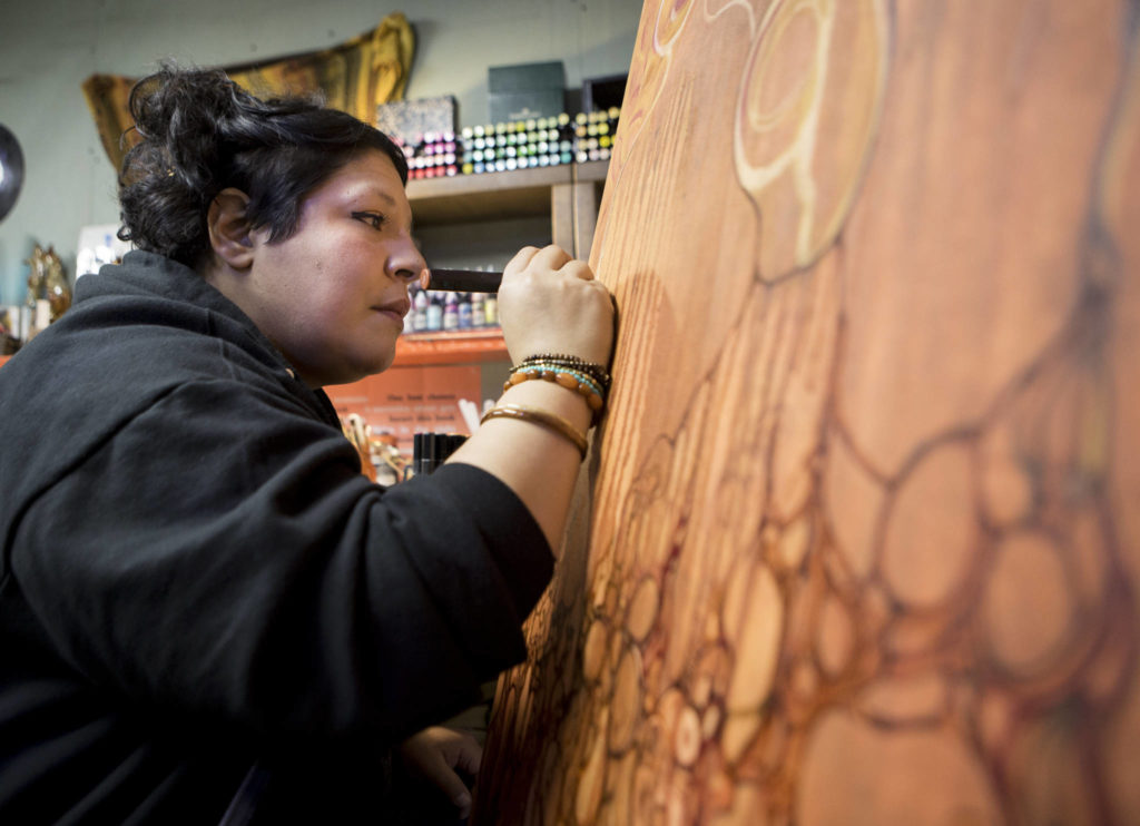 Luisana “Lu” Hernandez works on a large canvas piece titled “Madre Mia” in her Everett studio. (Olivia Vanni / The Herald)
