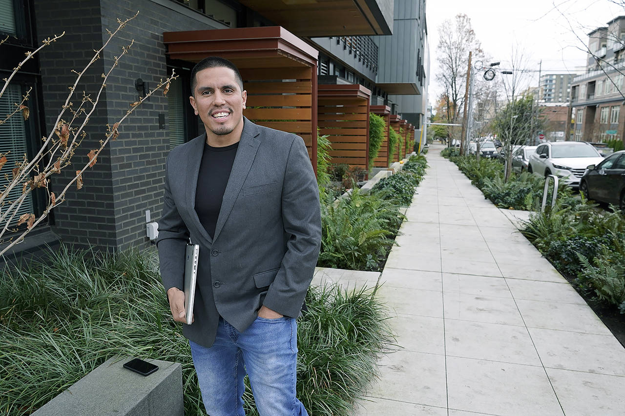 Victor Sauceda holds his laptop computer as he poses for a photo outside his apartment building Dec. 3 in Seattle. While serving eight years in prison for burglary and fencing stolen property, Sauceda learned computer coding and had a political awakening, and he’s now working to help restore voting rights to people in Washington state who are out on parole or probation after serving prison time. (AP Photo/Ted S. Warren)
