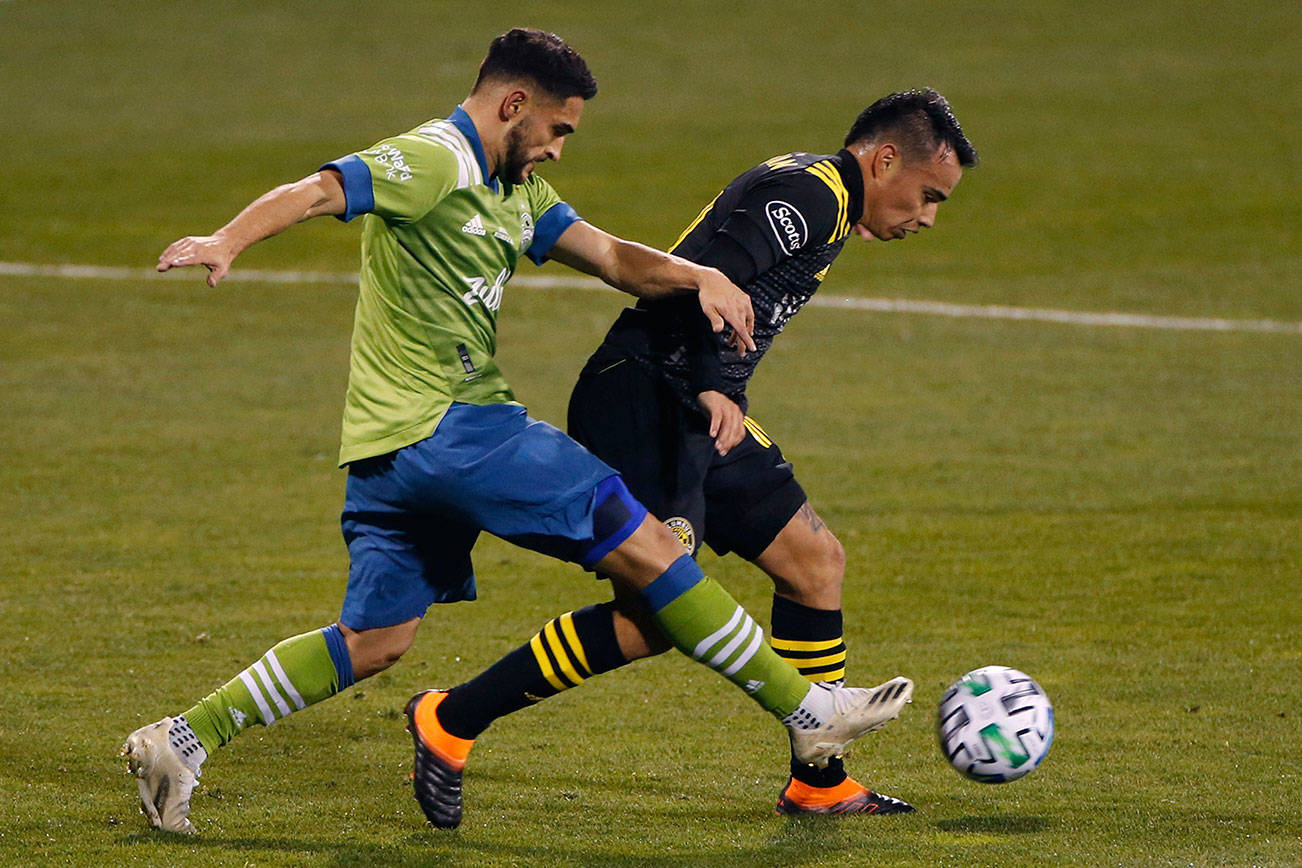 Seattle Sounders' Cristian Roldan, left, tries to dribble past Columbus Crew's Lucas Zelarayan during the first half of the MLS Cup championship soccer match Saturday, Dec. 12, 2020, in Columbus, Ohio. (AP Photo/Jay LaPrete)