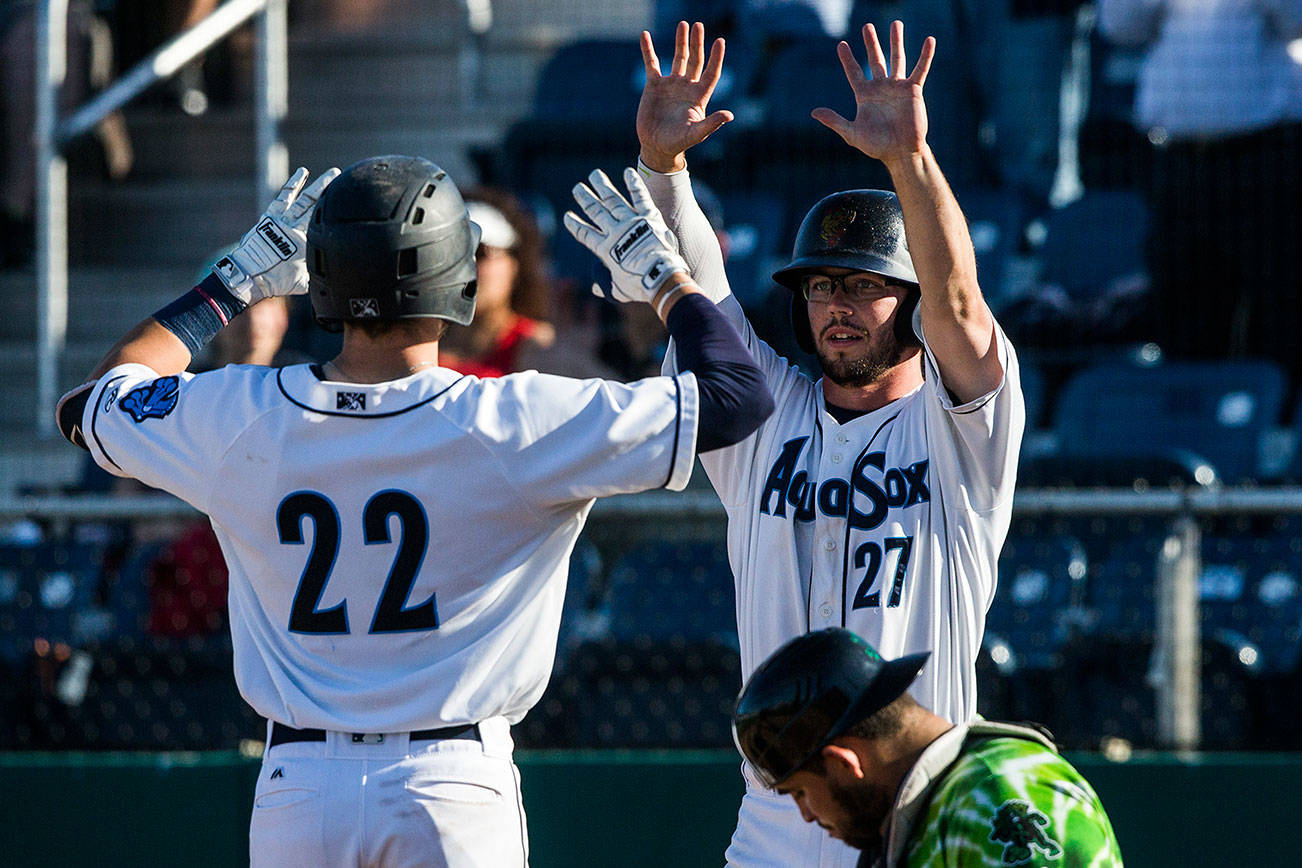 The Everett AquaSox’s Connor Hoover high-fives Carter Bins after scoring during a game against the Eugene Emeralds in 2019 at Funko Field. (Olivia Vanni / The Herald)