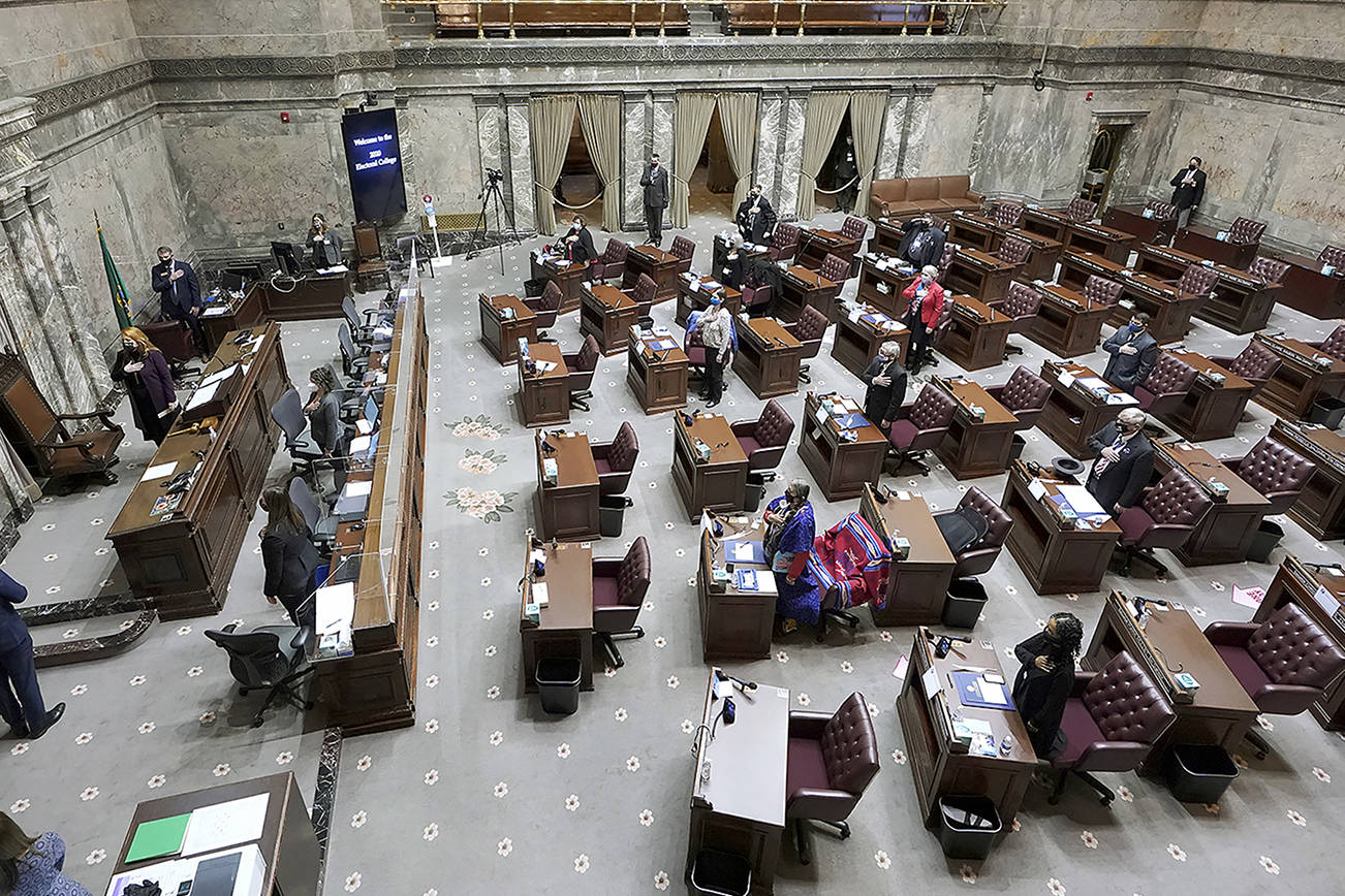 Members of Washington's Electoral College and other officials stand for the Pledge of Allegiance before casting their votes in the Senate Chamber at the state Capitol in Olympia, Wash., Monday, Dec. 14, 2020. (AP Photo/Ted S. Warren)