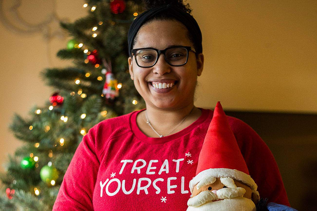 Simone Tarver, 30, whose mother sparked her collecting of Black Santas, at her home with two of her Santas on Saturday, Dec. 19, 2020 in Everett, Wa. (Olivia Vanni / The Herald)