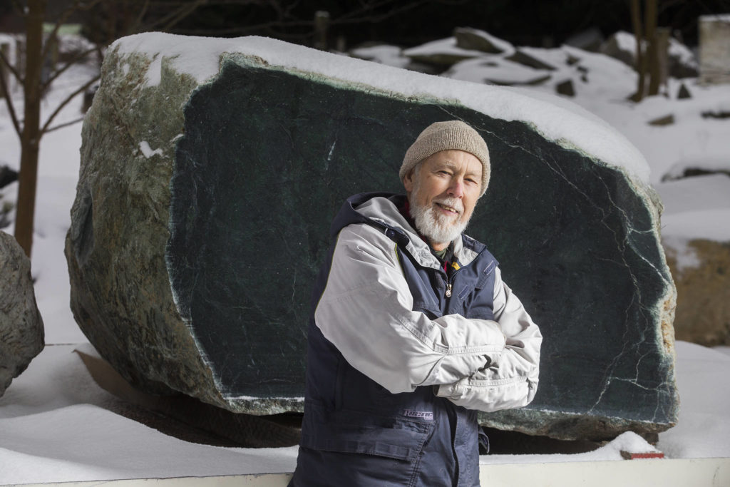 Arlington prospector Ed Molsee stands in front of a 16,000-pound jade boulder, he and fellow prospector Jason Henry, of Marblemount, discovered in the Darrington area. (Andy Bronson / Herald file)
