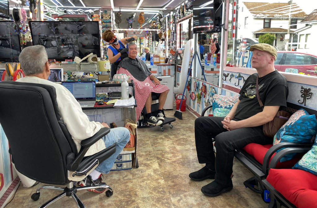 Brenda Humbert cuts Mike Murray’s hair while Bruce Best (right) waits his turn June 5 at the Barber Stop shop on Colby Ave. in Everett. On the left sits Brenda’s husband, Rex Humbert. (Sue Misao / The Herald)
