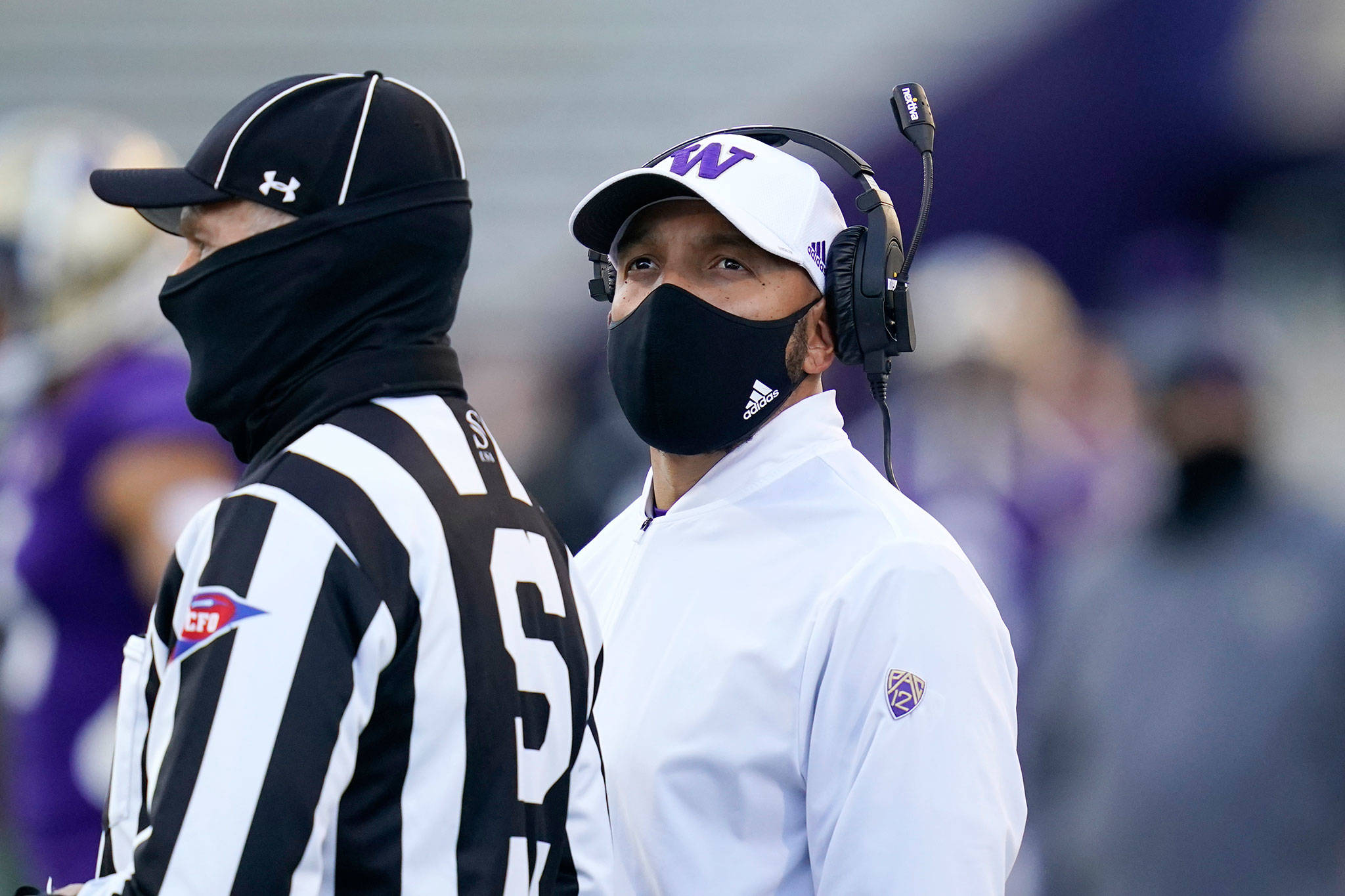 Washington coach Jimmy Lake stands with official Michael Weseloh as he waits for a review of a call during the second half of a game against Stanford on Dec. 5, 2020, in Seattle. (AP Photo/Elaine Thompson)