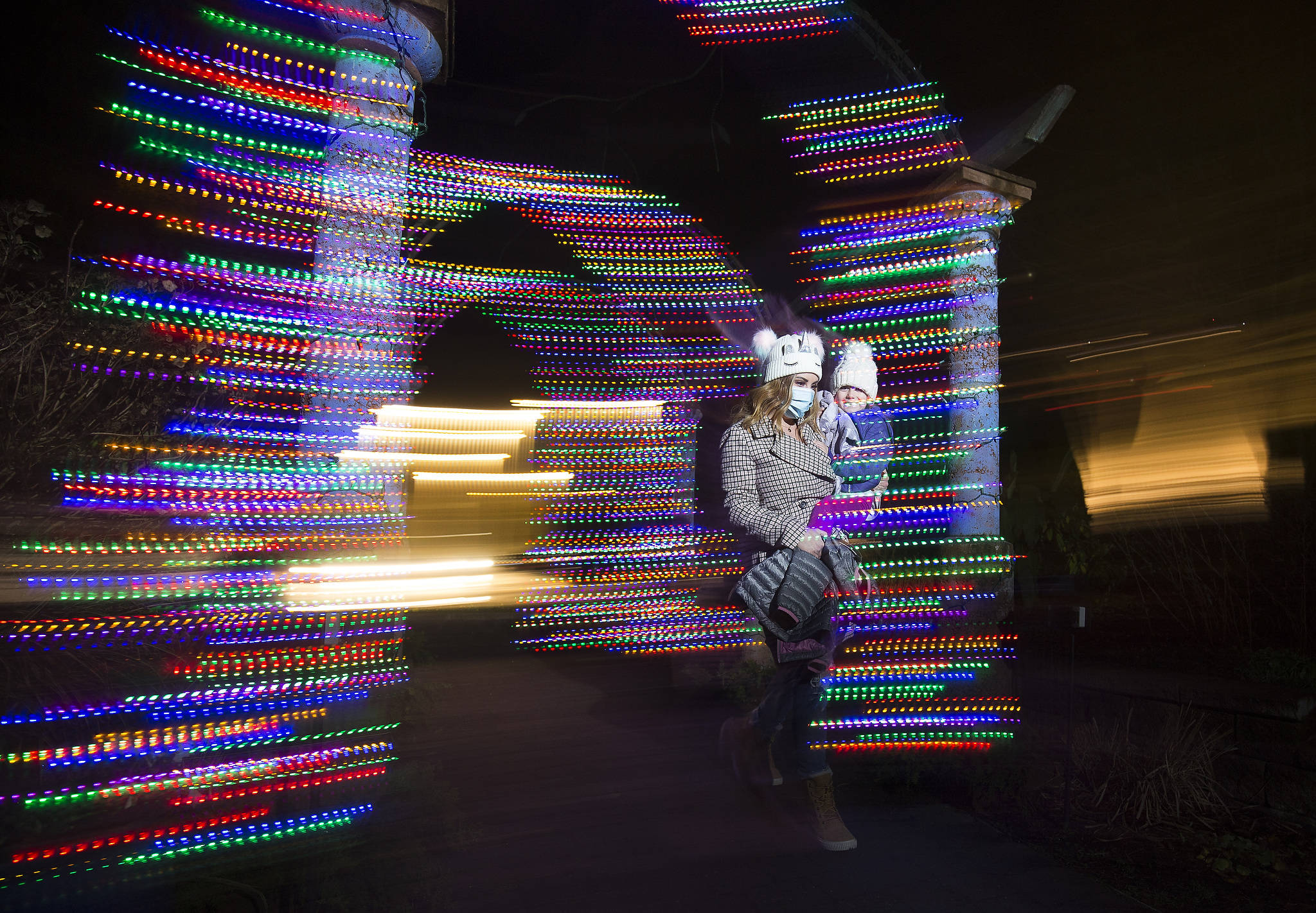 Chelsie Assink and her daughter, Paisley, of Bellingham, walk through lights at the front entrance of the Wintertide Lights at Evergreen Arboretum in Legion Park in Everett. For the first time, the Evergreen Arboretum is lit up for the holidays. Wintertide Lights will be up through New Year’s Eve and are open from dusk to 8 p.m. (Andy Bronson / The Herald)