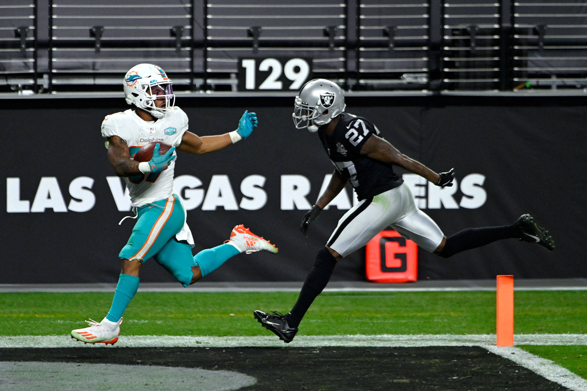 Dolphins running back and Lynnwood native Myles Gaskin (left) runs for a touchdown past Raiders cornerback Trayvon Mullen during a game Dec. 26, 2020, in Las Vegas. (AP Photo/David Becker)