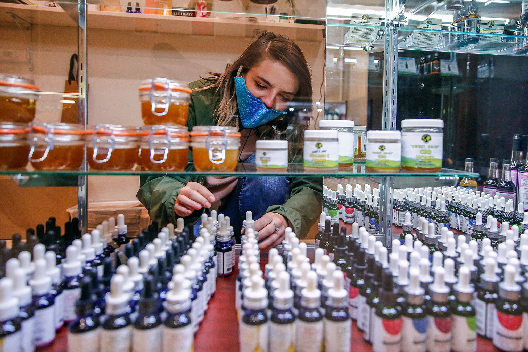 Store employee Cece Stafford arranges stock at Alchemy Health and Wellness CBD in Alderwood mall. (Kevin Clark / The Herald)