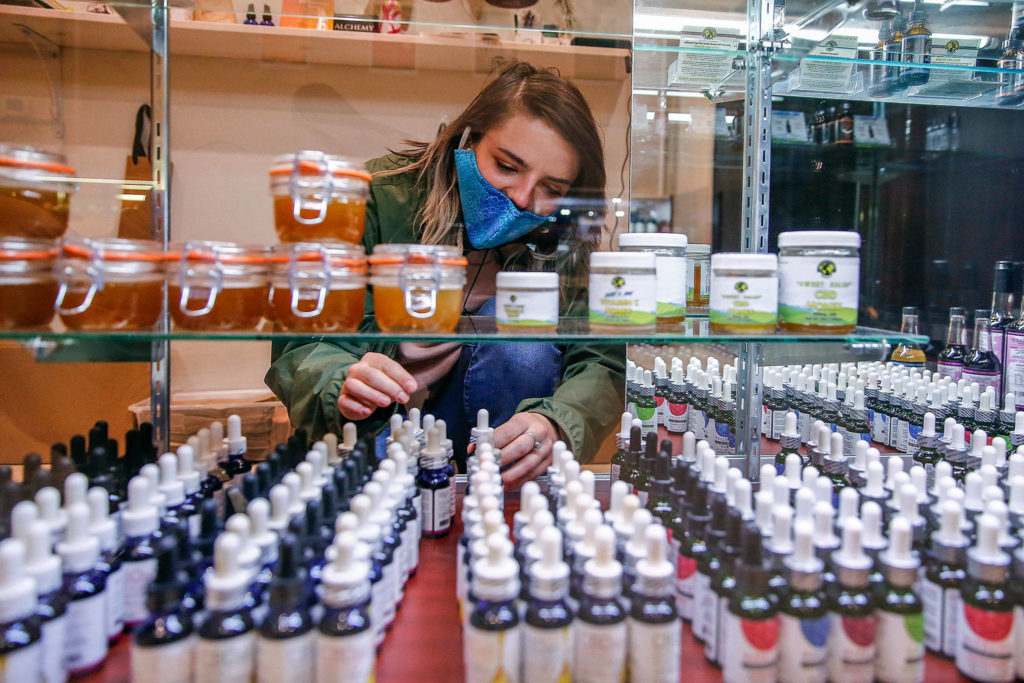 Store employee Cece Stafford arranges stock at Alchemy Health and Wellness CBD in Alderwood mall. (Kevin Clark / The Herald)
