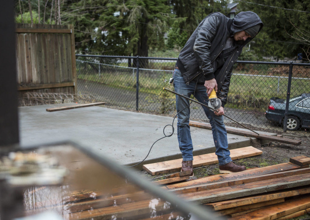 Dillon Carlson saws a piece of rebar for concrete being installed at a home in Lynnwood. (Olivia Vanni / The Herald)
