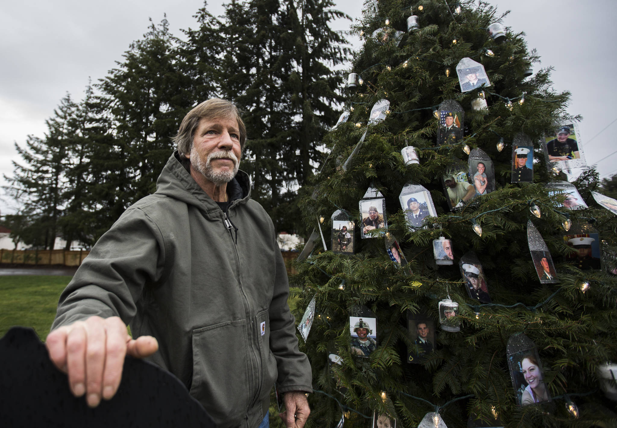 Patrick Crosby next to his tree with photographs of fallen military members, dedicated to Gold Star Mothers and Families, Wednesday on his property in Lynnwood. (Olivia Vanni / The Herald)