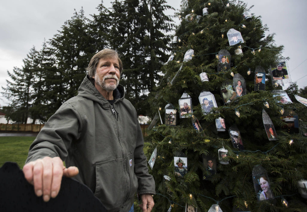 Patrick Crosby next to his tree with photographs of fallen military members, dedicated to Gold Star Mothers and Families, Wednesday on his property in Lynnwood. (Olivia Vanni / The Herald)
