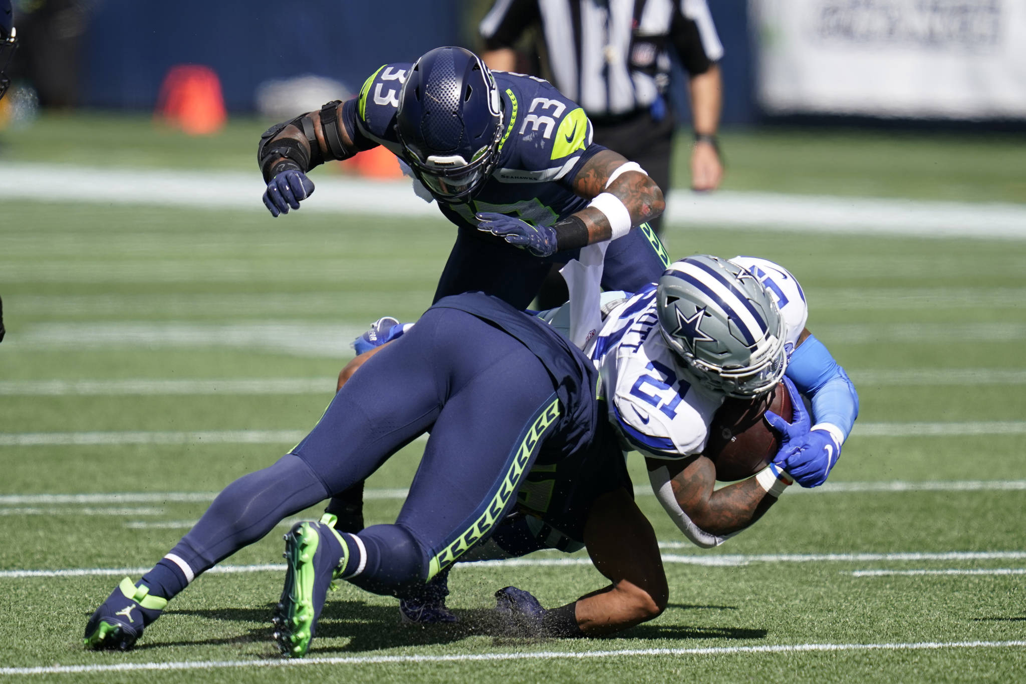 Seattle Seahawks middle linebacker Bobby Wagner and strong safety Jamal Adams (33) combine to tackle Dallas Cowboys running back Ezekiel Elliott (21) during their game on Sept. 27 in Seattle. (AP Photo/Elaine Thompson)