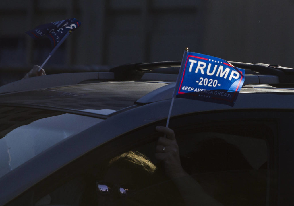 Trump supporters wave flags out of their car on Wednesday, Jan. 6, 2020 in Everett, Wa. (Olivia Vanni / The Herald)
