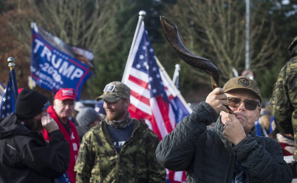 Steve Brown blows on a kudu horn as he and about 200 other Trump supporters rally at the 112th Street park-and-ride on Wednesday in Everett. (Andy Bronson / The Herald)
