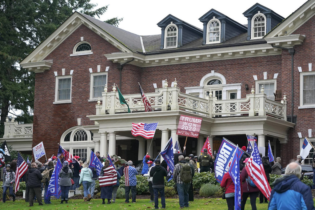Protesters stand outside the Governor’s Mansion after getting through a perimeter fence Wednesday at the Capitol in Olympia, following a protest against the counting of electoral votes in Washington, D.C., affirming President-elect Joe Biden’s victory. The area was eventually cleared by police. (AP Photo/Ted S. Warren)
