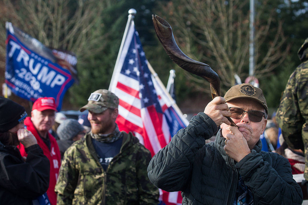 Steve Brown blows on a kudu horn as he and about 200 other President Trump supporters rally in the parking lot of the 112th Street Park and Ride on Wednesday, Jan. 6, 2020 in Everett, Wa. Brown referred to the horn as a Shofar, meaning "Victory". (Andy Bronson / The Herald)