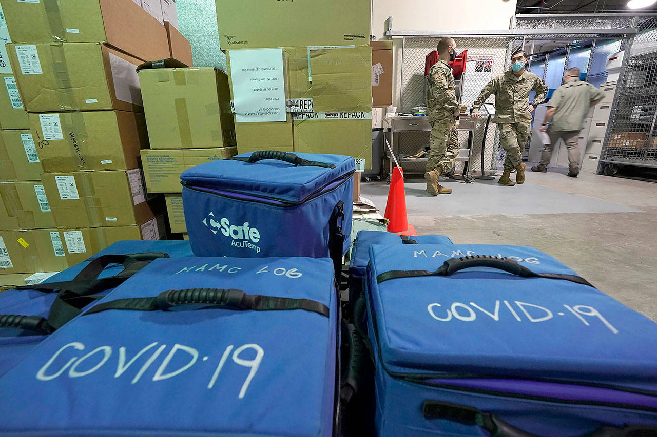 Soldiers working in a logistics area of Madigan Army Medical Center at Joint Base Lewis-McChord in Washington state stand, Dec. 15, 2020, near cooler bags that will be used to transport vials of the first shipment of the Pfizer vaccine for COVID-19 to other locations in the hospital when shots are given to workers on Wednesday. (Ted S. Warren / Associated Press file photo)