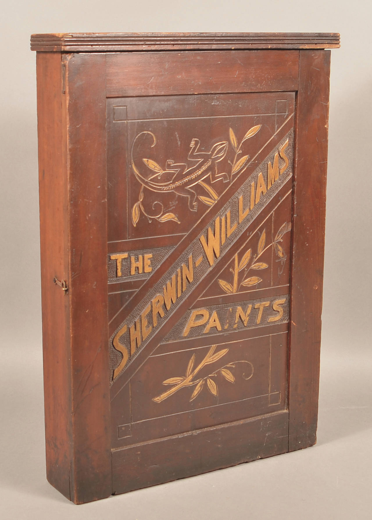This wooden cabinet with decorations and the name Sherwin-Williams is easy to date. A salamander is carved on the door suggesting a date before 1905 when the logo was changed. We wonder why a paint company used a salamander and not a chameleon that changed colors. Did the artist draw the wrong creature? (Cowles Syndicate Inc.)
