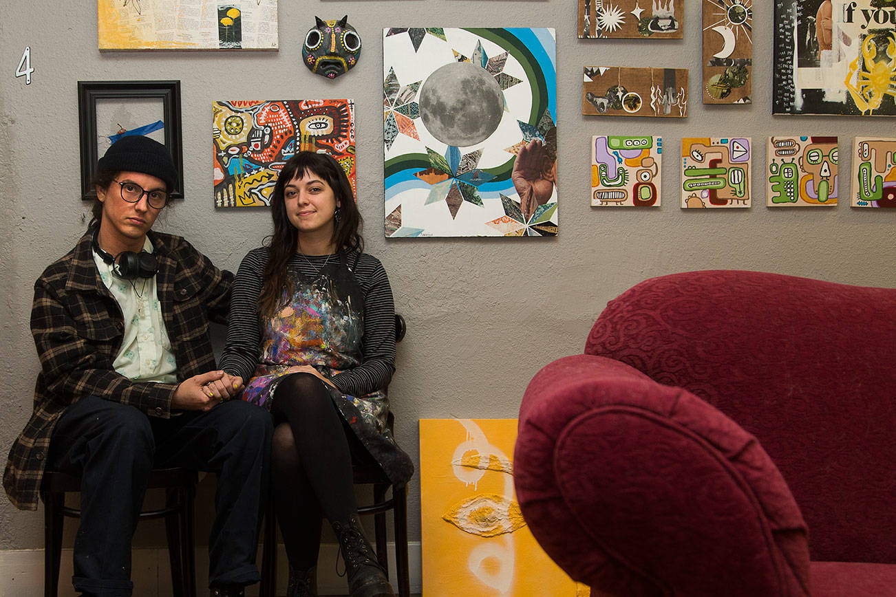 Artists Amber and Alex Vincini sit by examples of their artwork outside their studio on Wednesday, Jan. 13, 2020 in Everett, Washington.  (Andy Bronson / The Herald)