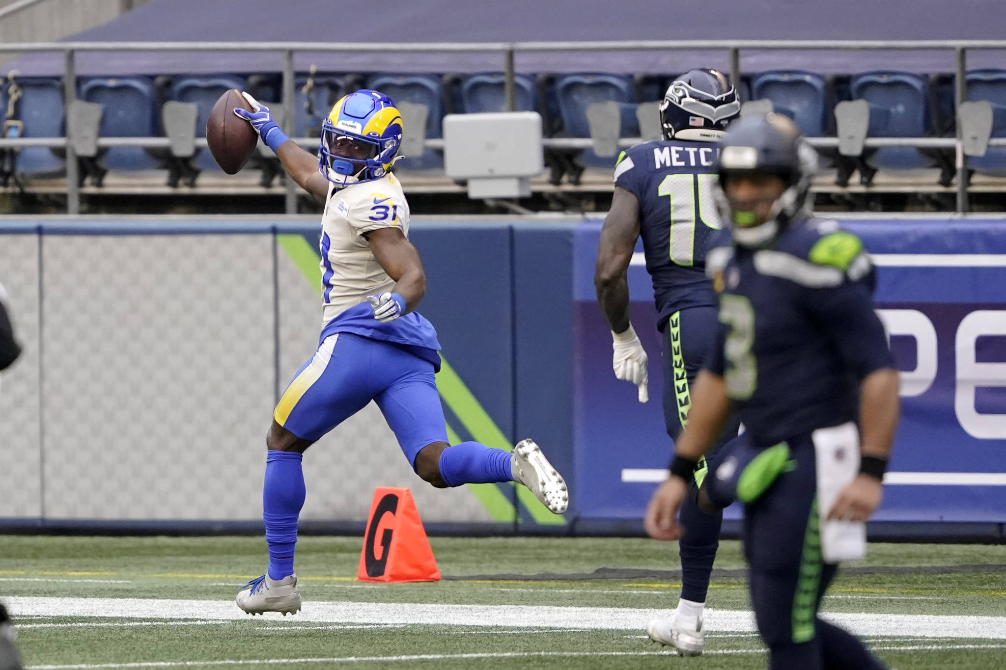 Los Angeles Rams defensive back Darious Williams (31) looks back as he scores on an interception from Seattle Seahawks quarterback Russell Wilson, right, during the first half of Sunday’s playoff game at Lumen Field. (AP Photo/Ted S. Warren)