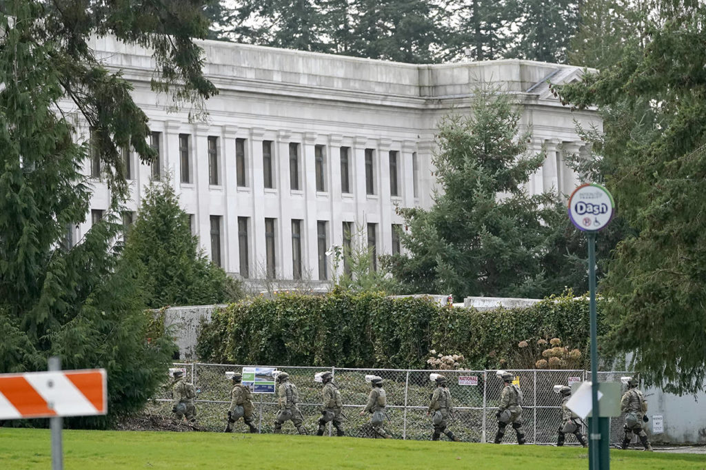 National Guard members march near a perimeter fence Sunday at the Capitol in Olympia. (AP Photo/Ted S. Warren)
