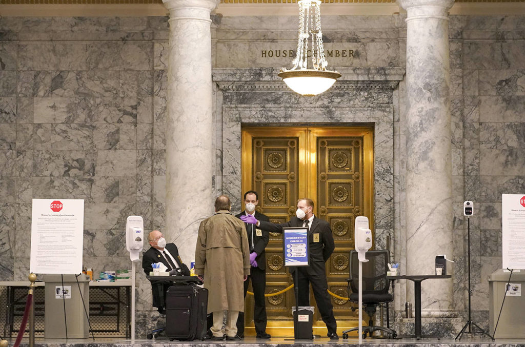 Staff members perform health checks at the entrance to the House Chambers Monday at the Capitol in Olympia. Washington state’s Legislature will open under a large security presence because of concerns about efforts by armed groups who might try to disrupt the proceedings or occupy the Capitol, which is closed to the public due to the ongoing pandemic. (AP Photo/Ted S. Warren)
