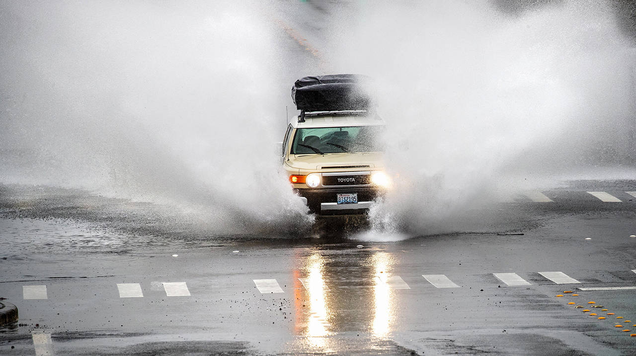 A car drives through a flooded street in Lynnwood after a rainstorm Jan. 4. (Mike Siegel/The Seattle Times via AP)