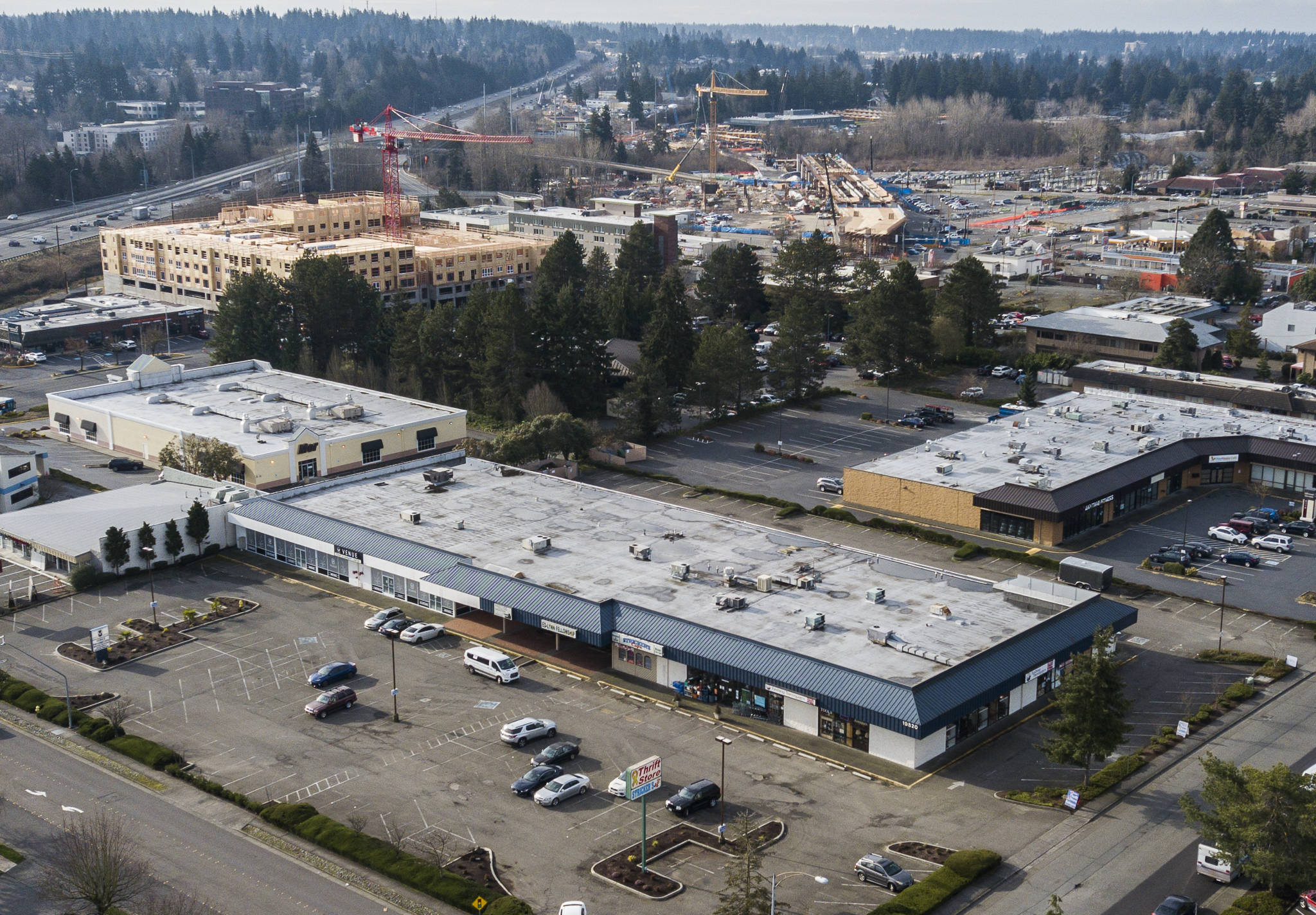 The Lynnwood strip-mall site (bottom) where Trent Development hopes to build 350 studio, one-bedroom and two-bedroom apartments. In the background is the Sound Transit Link light rail station that is under construction. (Olivia Vanni / The Herald)