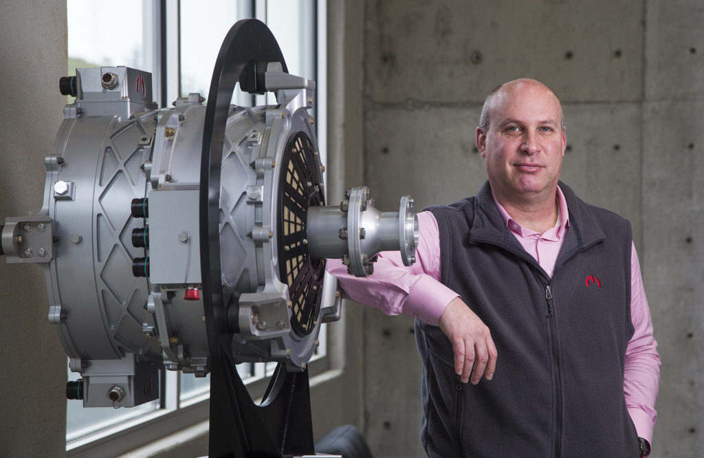 Roei Ganzarski, CEO of magniX, poses with a production electric engine, the magni500, at the company’s new headquarters on Seaway Boulevard in Everett. (Andy Bronson / The Herald)
