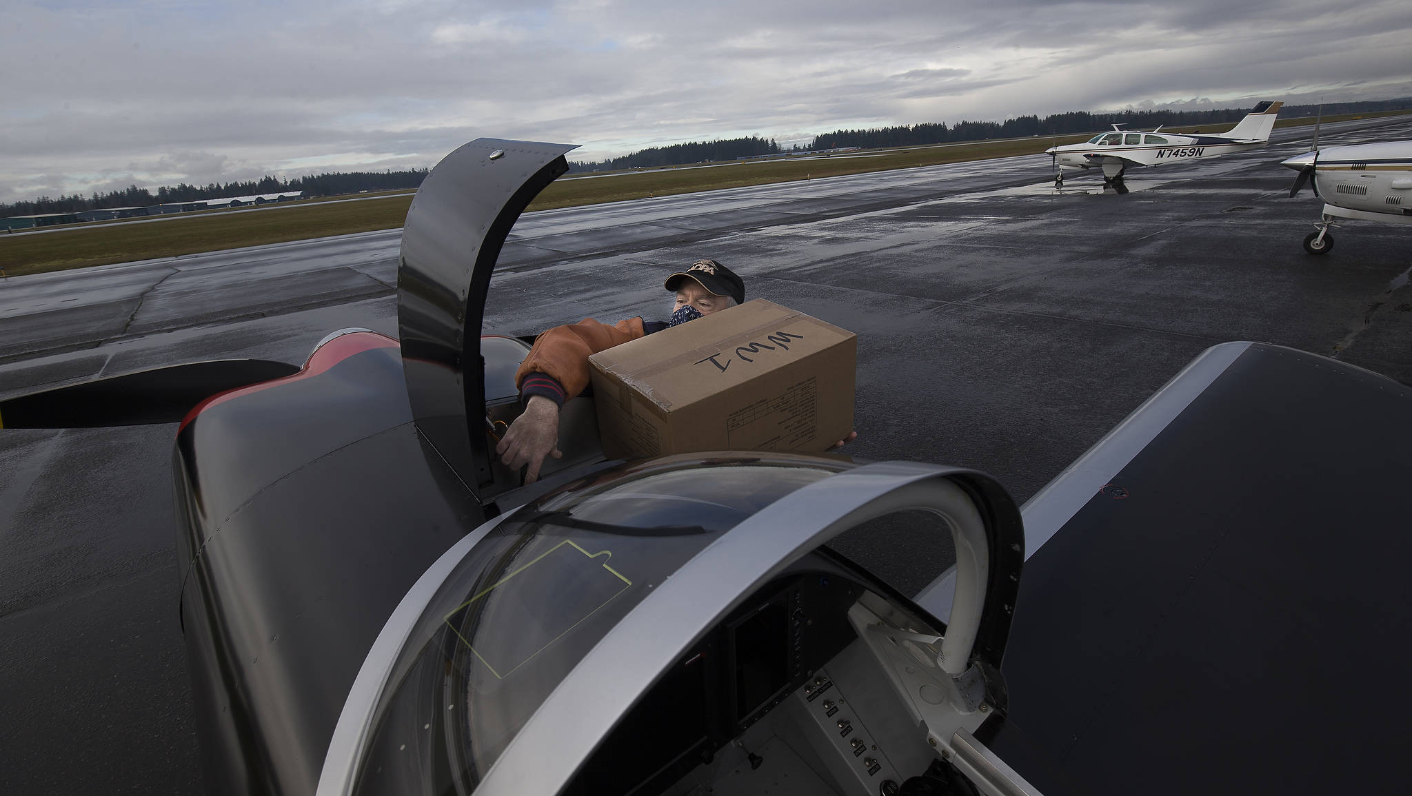 Ken Turpin struggles to fit a box of PPE into the front compartment of his RV-8 plane during an operation in which pilots delivered supplies to Native American tribes in Washington from Arlington Municipal Airport on Thursday. (Andy Bronson / The Herald)