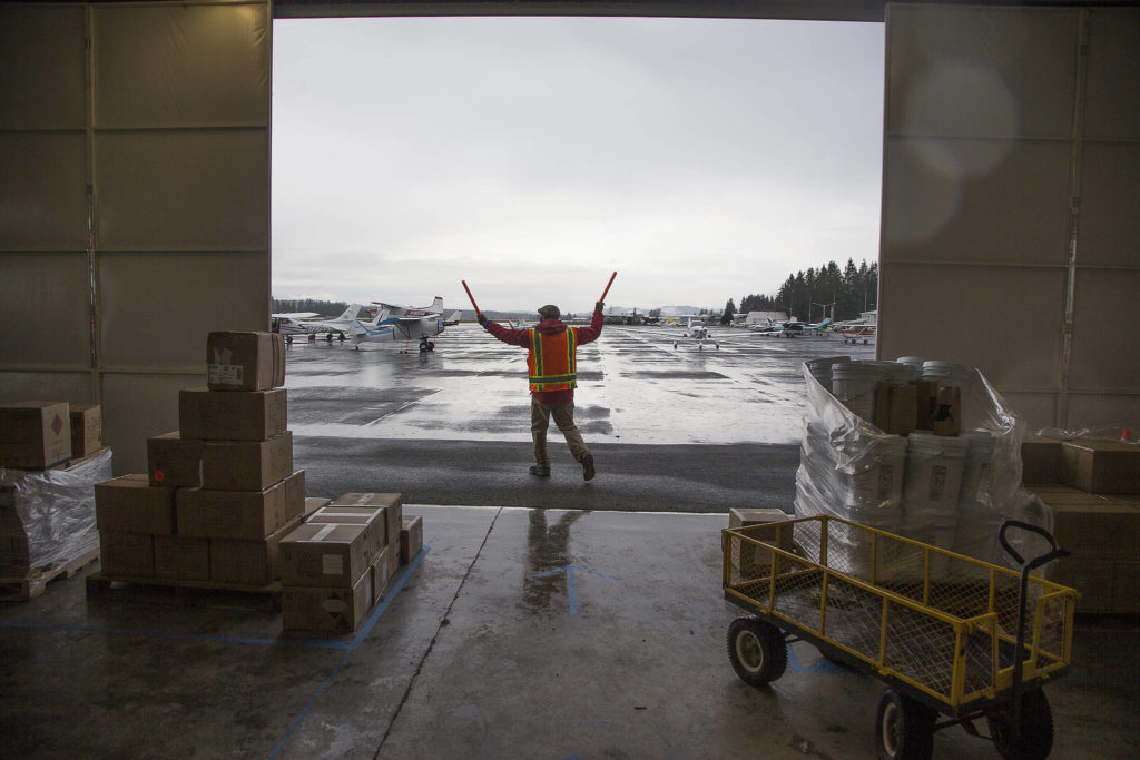 A volunteer directs a plane to a spot where it can be loaded with PPE supplies for an airlift to Native American tribes in Washington. (Andy Bronson / The Herald)
