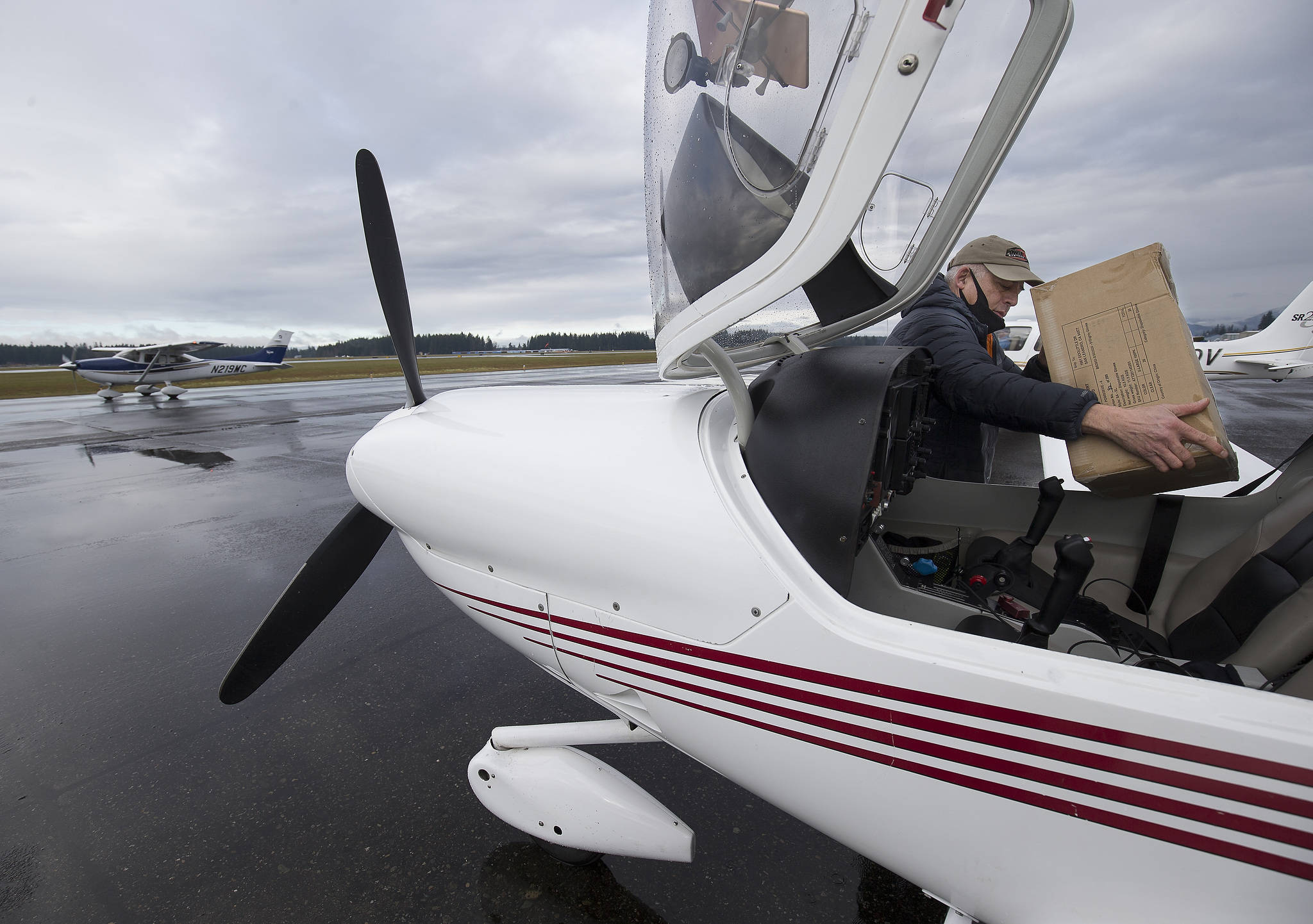 Pilot Greg Bell places a box into the passenger seat of his Diamond DA-40 plane as he prepares to airlift PPE supplies to Darrington from Arlington Municipal Airport on Thursday. (Andy Bronson / The Herald)