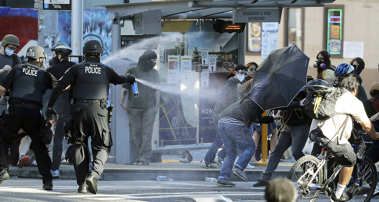 In this July 25, 2020 photo, police pepper spray protesters, near Seattle Central College in Seattle, during a march and protest in support of Black Lives Matter. (AP Photo/Ted S. Warren, File)