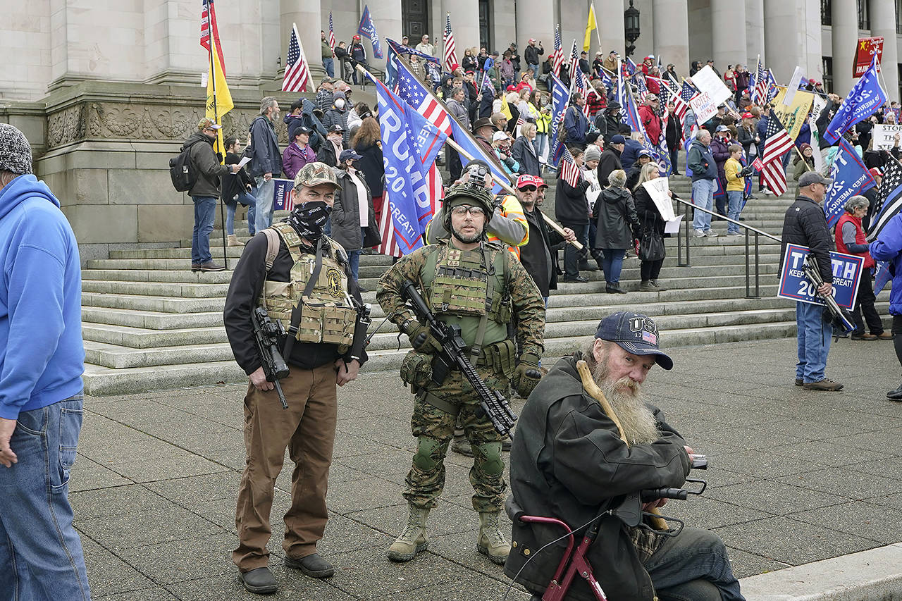 In this Jan. 6 photo at the Capitol in Olympia, two men stand armed with guns at a protest supporting President Donald Trump and against the counting of electoral votes in Washington, D.C. (AP Photo/Ted S. Warren, file)