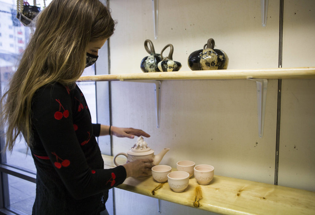 Rachel Recker places pottery on display at Salish Sea Ceramics in Everett. (Olivia Vanni / The Herald) 
