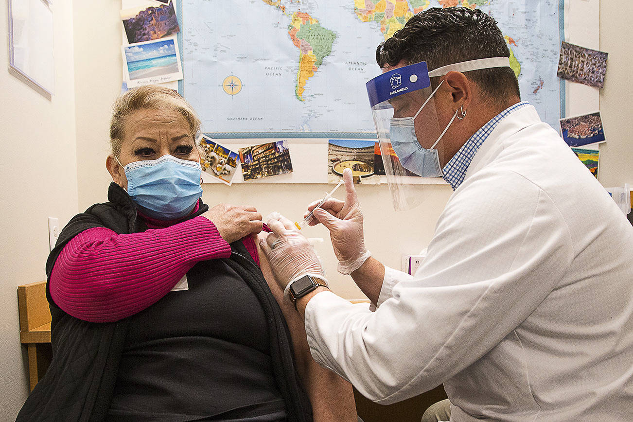 Alicia Ramos gets her first shot of the Modern COVID-19 vaccine from Pharmacy Director Jeremy Thompson at QFC on Thursday, Feb. 4, 2021 in Edmonds, Washington.  (Andy Bronson / The Herald)