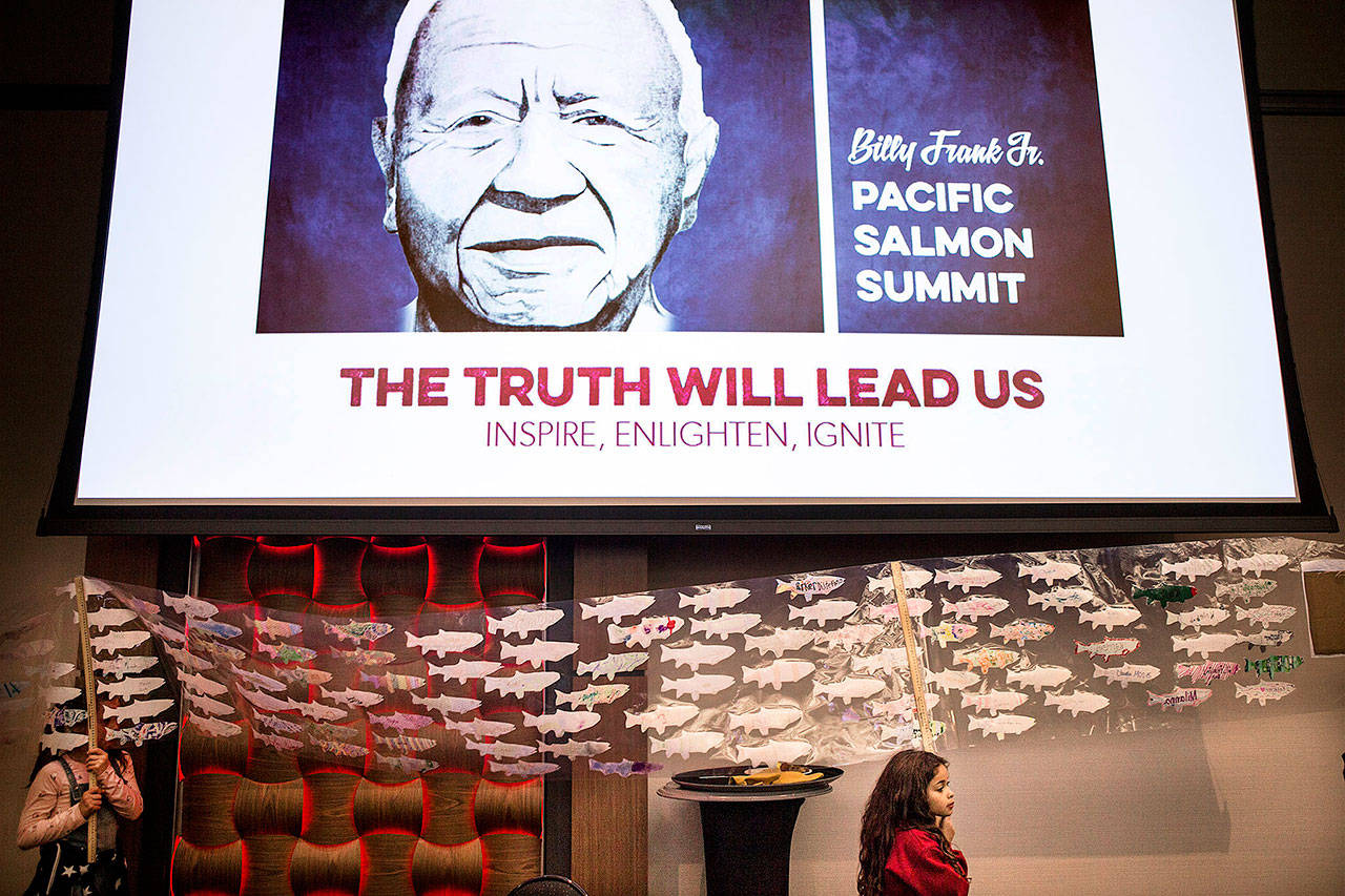 Aylani Lewis, holds up a banner sporting over 600 salmon cutouts, as she and Quil Ceda Tulalip Elementary students walk around the ballroom at The Billy Frank Jr. Pacific Salmon Summit at Tulalip Resort and Casino in March 2018. The state Legislature is considering a bill to honor Frank for his work on tribal fishing rights and the environment with a statue in Washington, D.C. (Andy Bronson / Herald file photo)