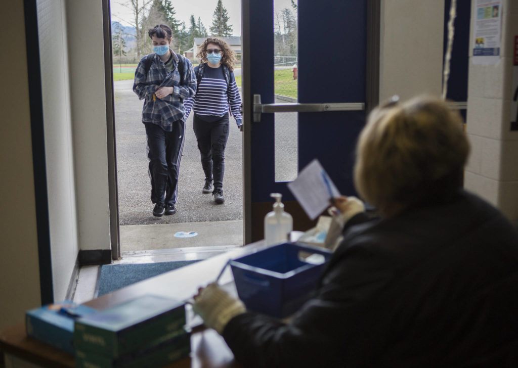 Students approach a checkpoint where they must fill out a wellness survey before having their temperatures checked at Sultan High School. (Olivia Vanni / The Herald) 
