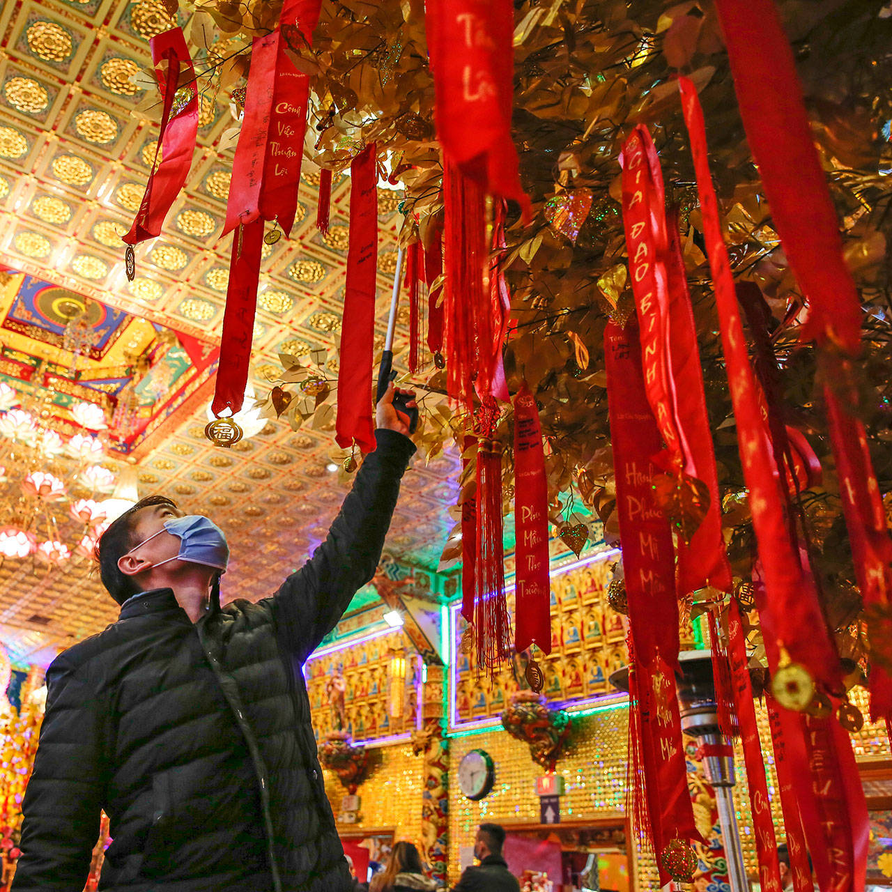 Helio Liu attaches a wish to The Wishing Tree in celebration of Lunar New Year at Dia Tang Temple in Lynnwood on Friday. (Kevin Clark / The Herald)