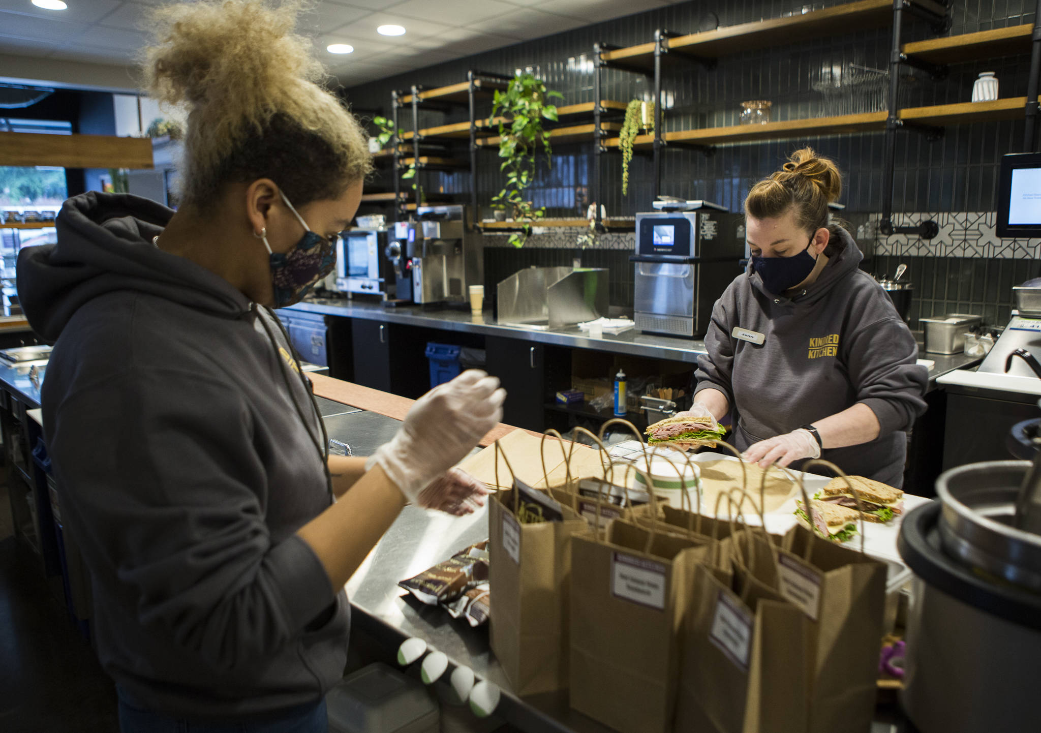 Shianne Shelton (left) and Jennifer Smith (right) prepare sandwich lunches to be delivered to the volunteers the the Arlington Airport COVID-19 vaccination site Friday in Everett. (Olivia Vanni / The Herald)