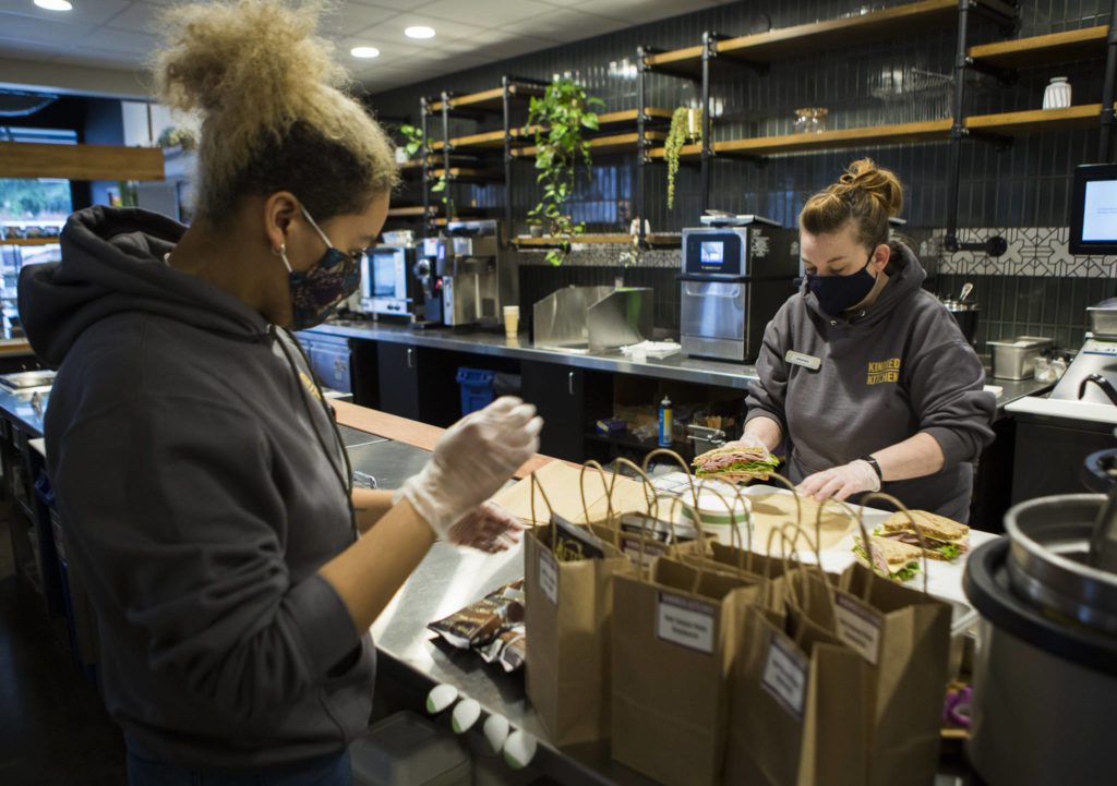 Shianne Shelton (left) and Jennifer Smith (right) prepare sandwich lunches to be delivered to the volunteers the the Arlington Airport COVID-19 vaccination site Friday in Everett. (Olivia Vanni / The Herald)
